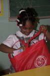 Happy student from St John Christian Academy looks in her gift bag from Santa